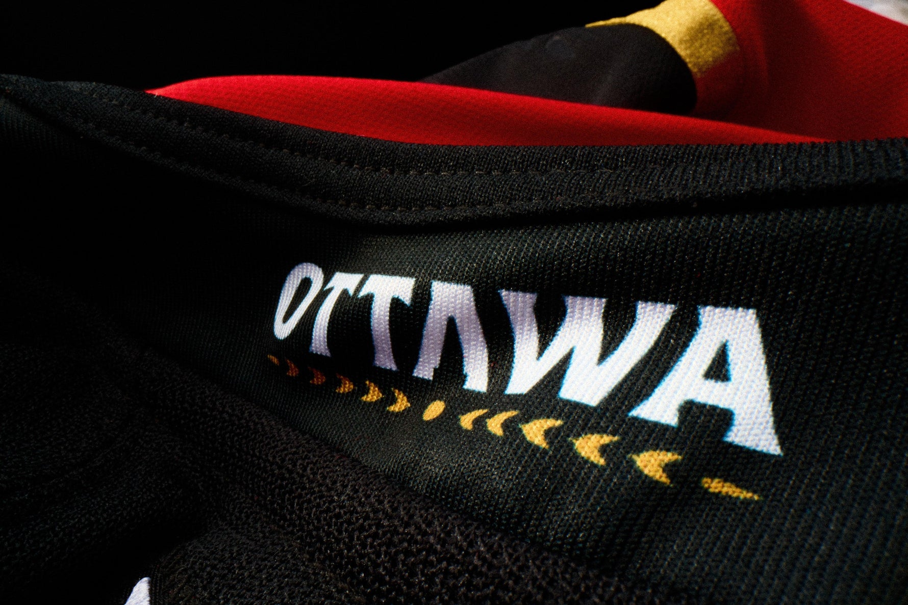Close-up of a Ottawa Senators Jersey with 'Ottawa' printed on it, featuring red and yellow accents.